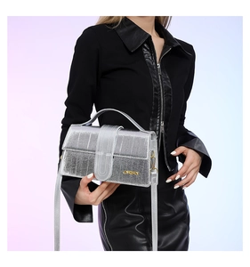 Detail of silver metallic textured crossbody bag with gold logo and reinforcement strap