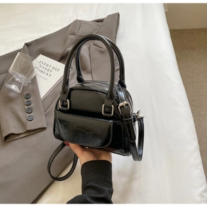 Close-up of black glossy leather Boston bag with silver hardware and detachable strap