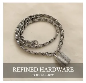Détail de la bandoulière en chaîne argentée et boucle rayée d'un sac seau métallisé