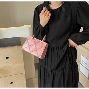 Pink quilted handbag with gold hardware shown on model with black pleated dress