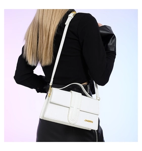 Detail of white crocodile pattern shoulder bag with golden brand logo and thin strap