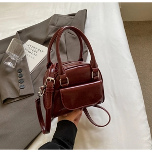 Macro shot of dark red glossy shell bag with silver hardware and top handle detail