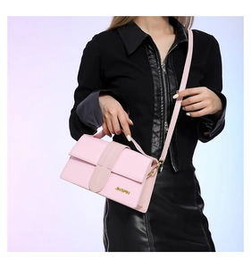 Detailed close-up of pink leather handbag showing golden logo and refined texture