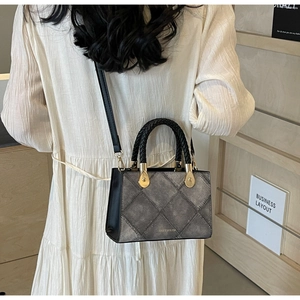 Detail view of the quilted texture and contrast stitching on a two-tone crossbody handbag