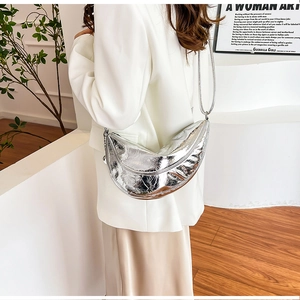 Silberne Halbmond-Schultertasche mit metallischer Knitteroptik von Model getragen