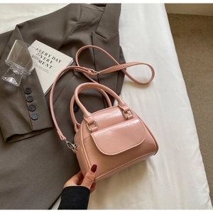 Detailed view of a pink shell-shaped mini handbag on soft white bedding with grey blazer