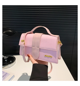 Detail of pink faux crocodile leather handbag with golden logo and detachable strap