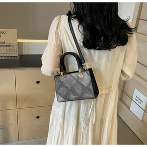 Detail of grey quilted handbag with braided handle and adjustable shoulder strap worn by model