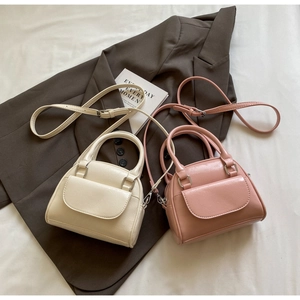 Detail view of mini PU leather shell bags in beige and pink on a brown blazer