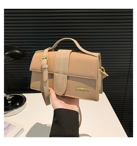 Detail of beige faux crocodile pattern leather handbag with gold logo and U-shaped stitching