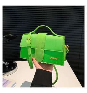 Close-up of neon green crocodile texture handbag with adjustable strap and metal logo