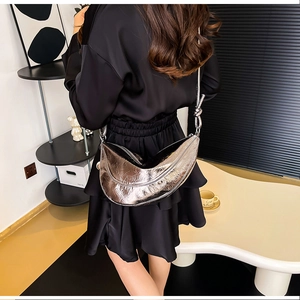 Detail der silbernen halbmondförmigen Tasche mit Metallic-Textur und elegantem Knoten