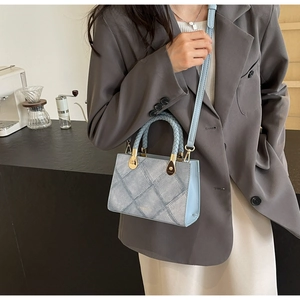 Detail of light blue quilted crossbody bag with woven handles and golden hardware