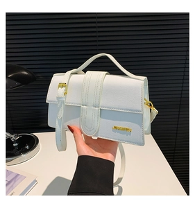 Close-up of white crocodile pattern bag featuring golden hardware and logo detail