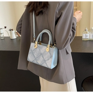 Detail of light blue denim texture small square bag with woven handle and gold hardware