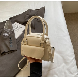 Detail view of a cream-white mini Boston bag with front flap pocket and silver hardware