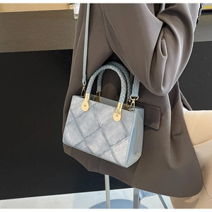 Detail of light blue crossbody bag with denim texture and woven handle on model