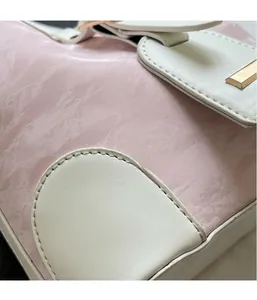 Nahaufnahme der rosa Textur und weißen Nähte einer Beuteltasche mit goldenen Beschlägen