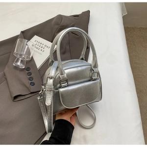 Close-up of a metallic silver shell bag with wrinkled texture on a chic brown suit