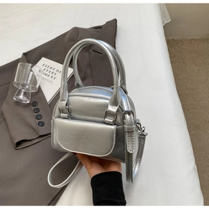 Detail of silver metallic shell bag showing wrinkled texture and crossbody strap
