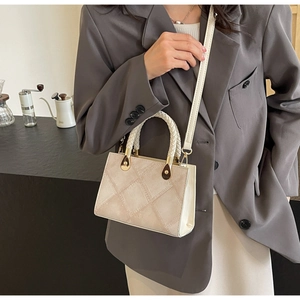 Detail of quilted leather handbag with woven handle and elegant gold metal hardware