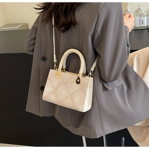 Detailed view of beige woven handle and diagonal quilted texture on women's crossbody bag