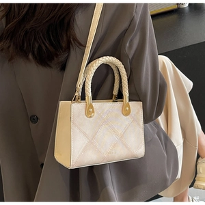 Detail of crossbody box bag with woven handle and pearlescent quilted texture