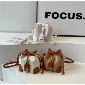 Drei stylische Kontrast-Eimertaschen auf weißen Podesten mit Focus-Hintergrund