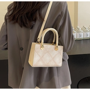 Detail of cream white quilted handbag with woven handle on grey blazer