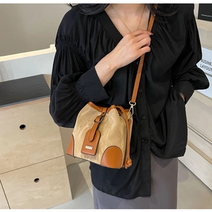 Detail der Kontrast-Beuteltasche mit Marmortextur und braunem Lederbesatz am Modell