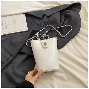 Détail du sac seau blanc brillant avec bandoulière en chaîne et boucle en métal