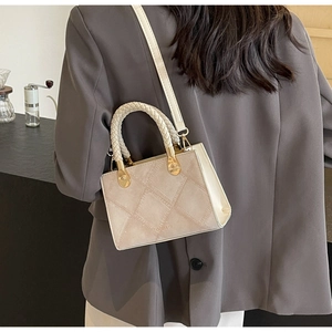 Detail of beige quilted handbag with woven handles and FASHION&YM logo on grey blazer
