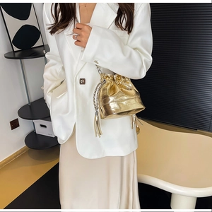 Sac seau doré chic avec texture métallisée froissée et détail de pompon sur mannequin