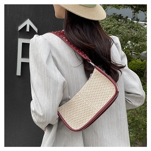 Detail of straw baguette bag with burgundy leather trim and silver studded shoulder strap