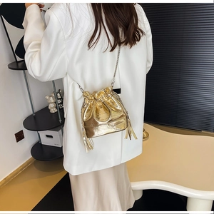 Détail d'un sac seau doré métallisé avec franges élégantes et bandoulière chaîne