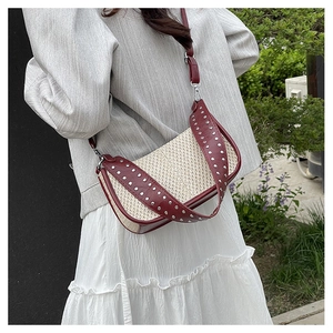 Détail du sac tressé en demi-lune avec rivets argentés et finitions en cuir bordeaux