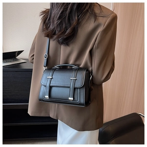 Close-up of black litchi pattern leather crossbody bag on a brown blazer outfit