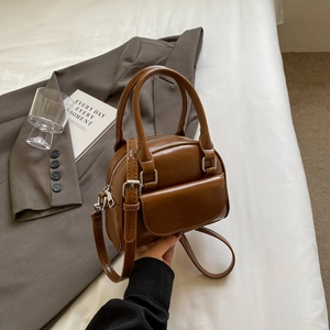 Retro brown shell bowling bag with double handles and adjustable strap in urban setting