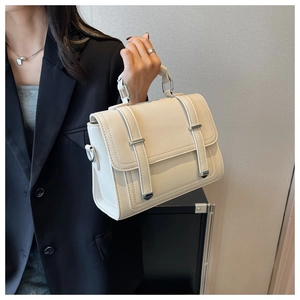 Detail of a creamy beige lychee textured leather handbag with silver metal hardware accents