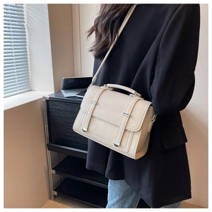 Detail view of a cream minimalist crossbody bag with silver hardware and adjustable strap