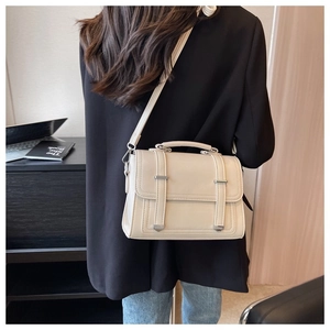 Detail of cream faux leather crossbody bag with silver buckles and vertical straps