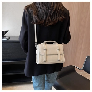 Close-up of minimalist cream PU leather crossbody bag worn by a model in a modern style