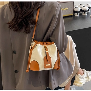 Schicke Bucket Bag in Beige und Braun, kombiniert mit einem grauen Freizeit-Blazer