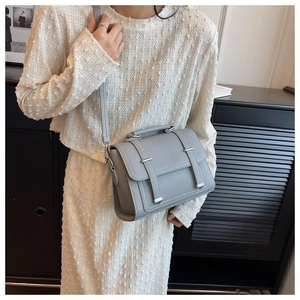 Detail of grey pebbled leather crossbody bag with silver hardware on a fashion model