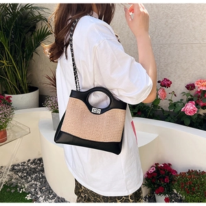 Détail du sac seau bicolore en paille tressée, panneaux de cuir et fermoir en métal
