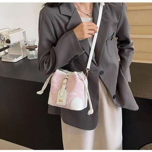 Detail der pink-weißen Eimertasche mit Kordelzug und schmalem Leder-Schultergurt