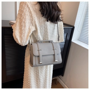 Detail of grey PU leather crossbody bag featuring silver metallic buckles and top handle