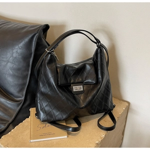 Détail du sac cabas matelassé noir avec fermoir rotatif métallique et bandoulière chaîne
