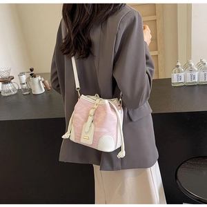 Detail der Kontrast-Beuteltasche mit rosa Textur und weißem Lederriemen am Modell
