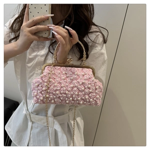 Détail d'une pochette rose en dentelle avec perles, cadre doré et anse en métal